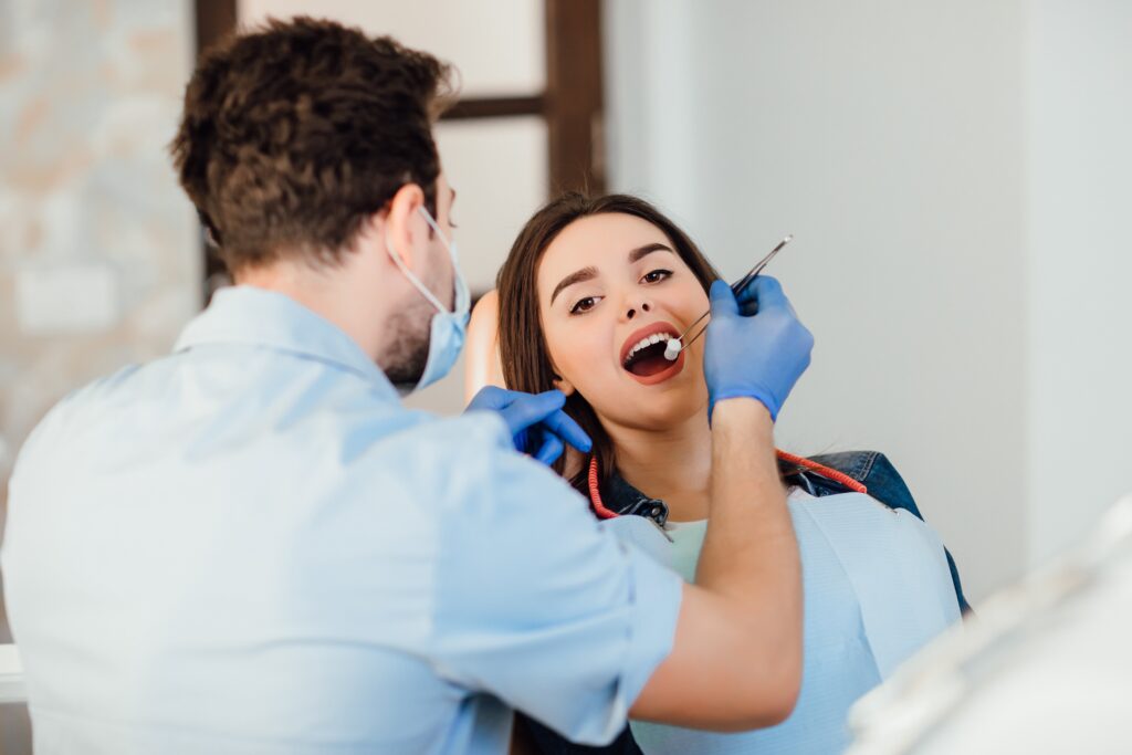 dentist-making-professional-teeth-cleaning-withb-cotton-female-young-patient-dental-office-min